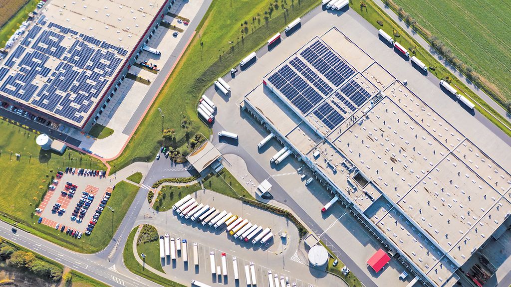 Industry with low carbon footprint. Industrial warehouses with solar panels on the roof. Technology park and factories from above.