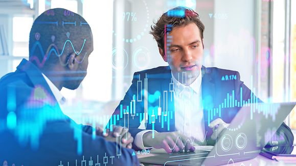 Two businessmen working together, forex diagrams hologram and big business data analysis. Double exposure hologram with candlesticks and chart. Concept of teamwork and trading