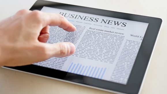 Man hands are pointing on touch screen device with business news.