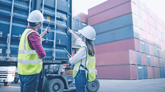 Foreman control loading Containers box from Cargo for import export. Worker looking on the facilities with purposefulness and energy to complete job. 