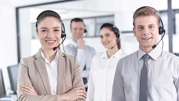 Group of happy, cheerful call center workers are smiling and looking at the camera