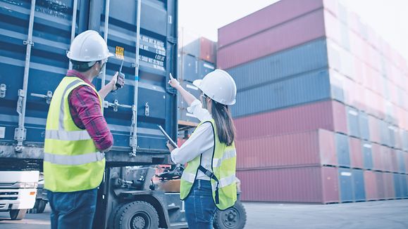 Foreman control loading Containers box from Cargo for import export. Worker looking on the facilities with purposefulness and energy to complete job.