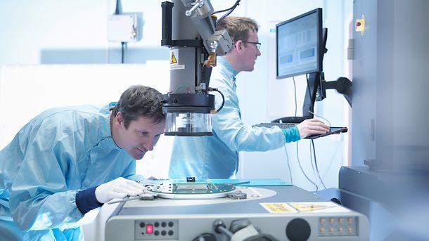 Electronics workers checking components in clean room laboratory