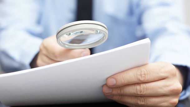 Businessman looking through a magnifying glass to contract