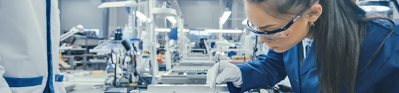 Shot of an Electronics Factory Workers Assembling Circuit Boards by Hand While it Stands on the Assembly Line. High Tech Factory Facility.