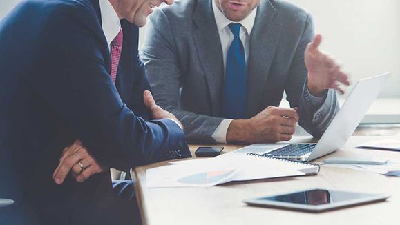 Businessmen working together on a laptop.