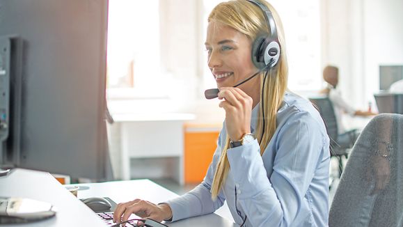 Tech support female operator communicating with client using handset