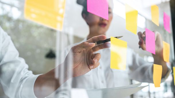 Young creative team professional using post it notes in glass wall to writing strategy business plan to development grow to success.