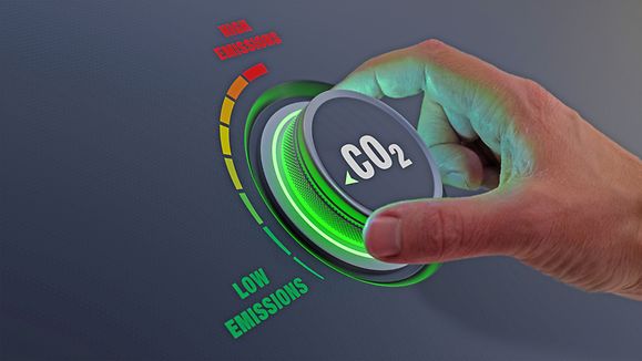 Lower CO2 emissions to limit global warming and climate change. Concept with manager hand turning knob to reduce levels of CO2. New technology to decarbonize industry, energy and transport